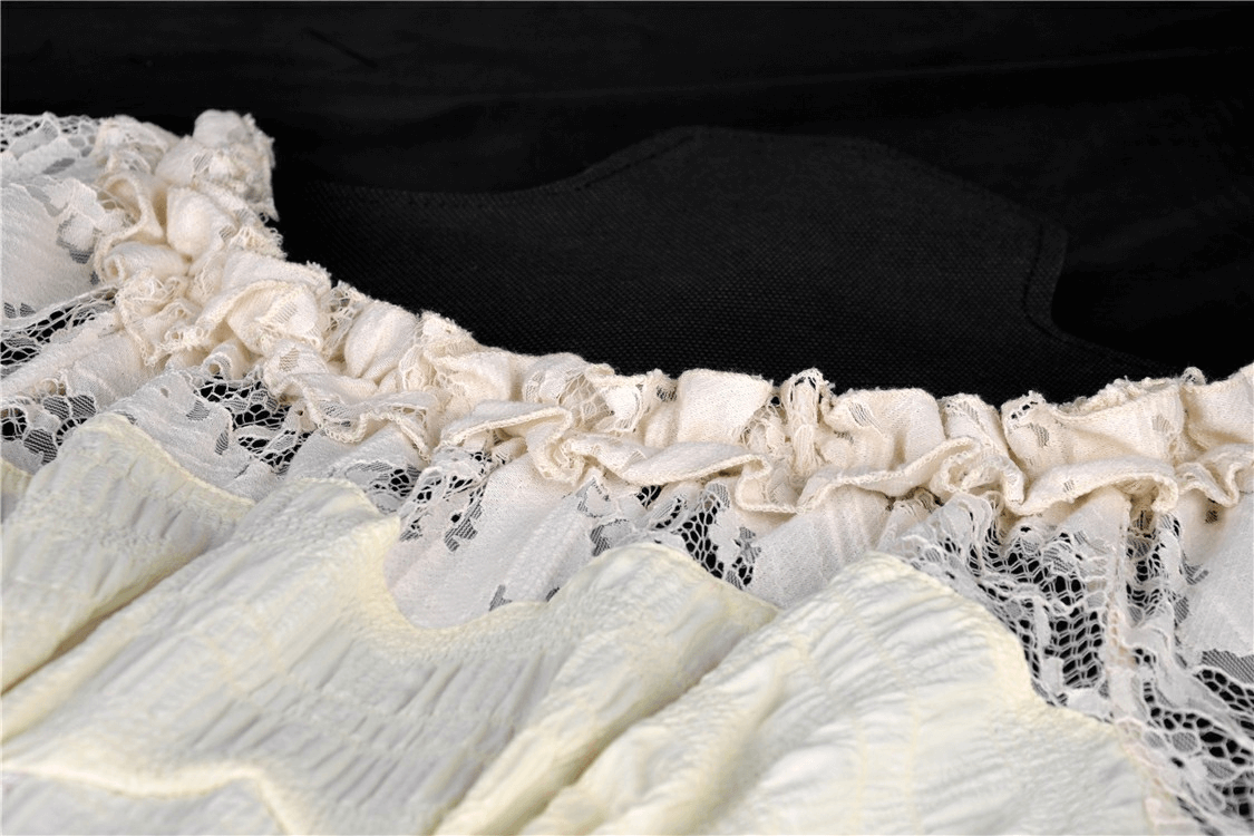 Close-up of vintage lace detailing on off-shoulder dress, showcasing intricate ruffles and elegant texture.