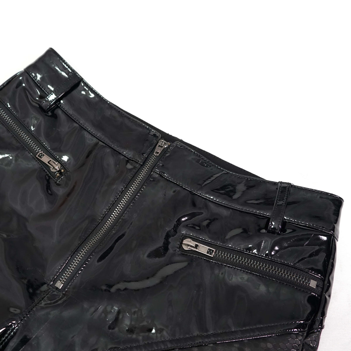 Close-up of cyberpunk women's black PU leather pants with stylish zip pockets and a shiny finish.