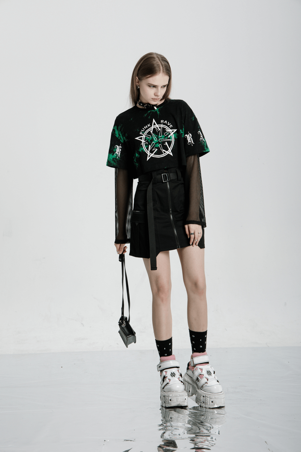 Model showcasing edgy rebel asymmetrical zippered tactical skirt with graphic tee and bold accessories.