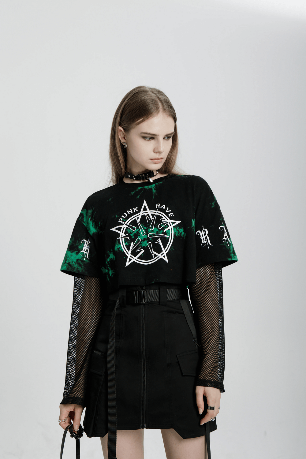 Model showcasing an edgy asymmetric high waist tactical skirt with a punk graphic tee and mesh sleeves.