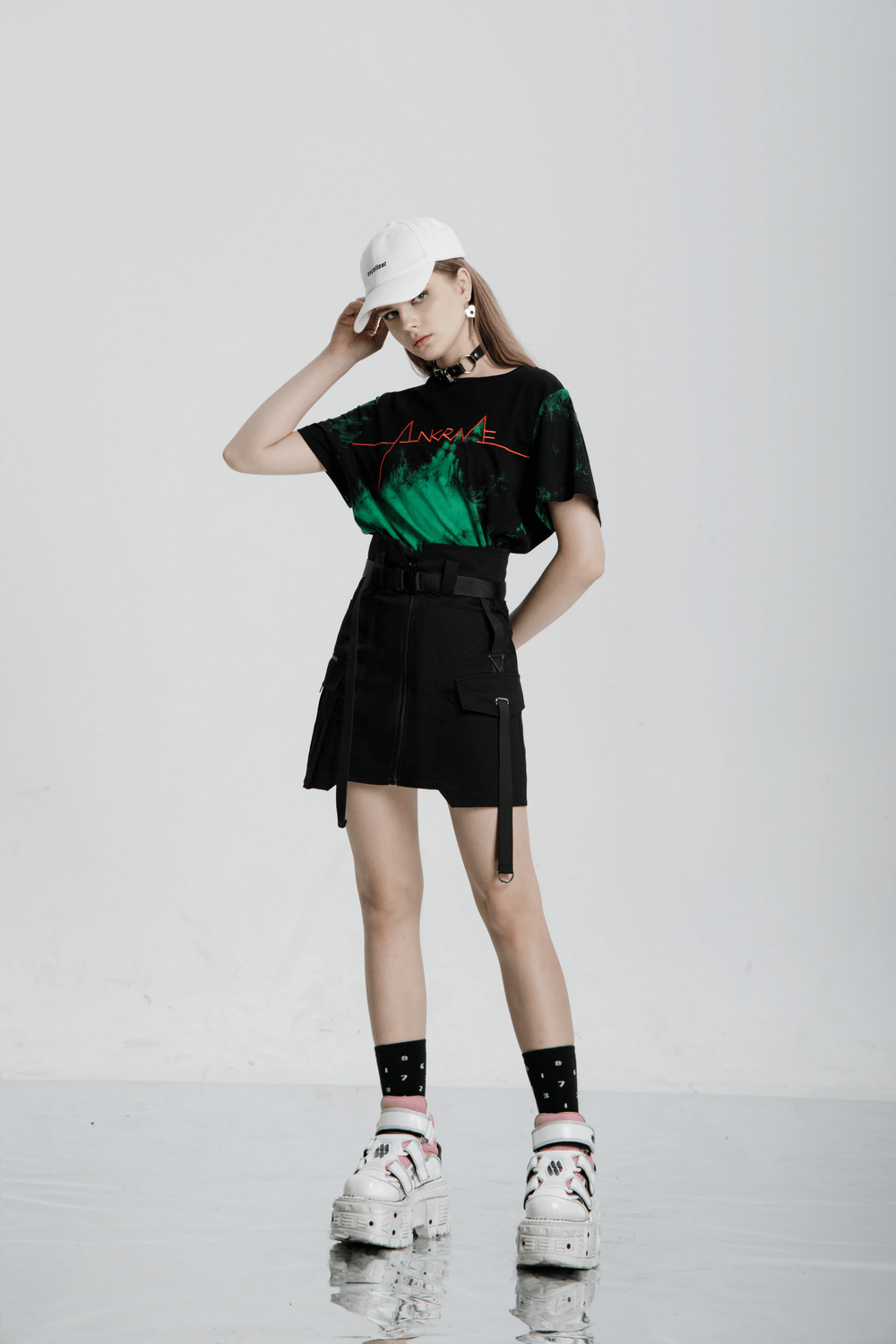 Model showcasing a stylish high waist tactical skirt paired with a graphic tee and sporty accessories.