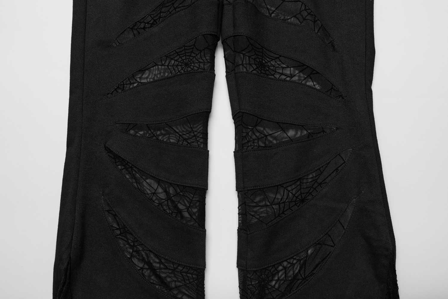 Black flared pants featuring spiderweb mesh cutouts for a gothic fashion statement.