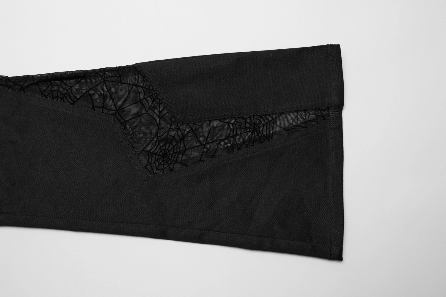 Close-up of black flared pants with spiderweb mesh detailing for a goth-inspired look.