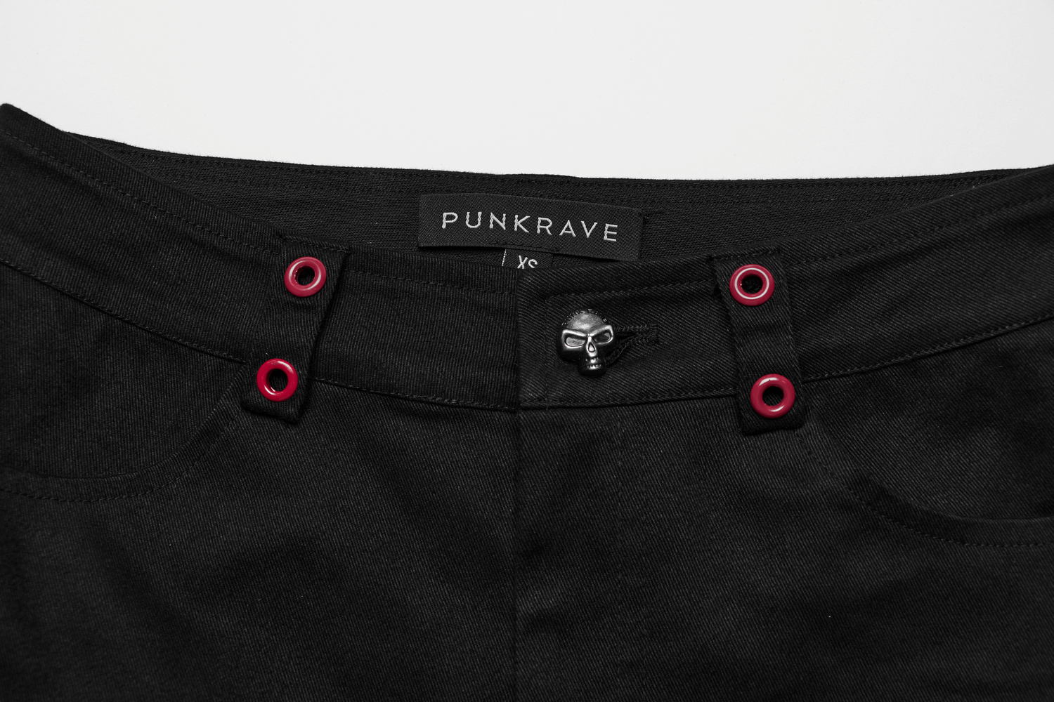Close-up of Gothic flared pants featuring skull accent button and red eyelets from PUNKRAVE.
