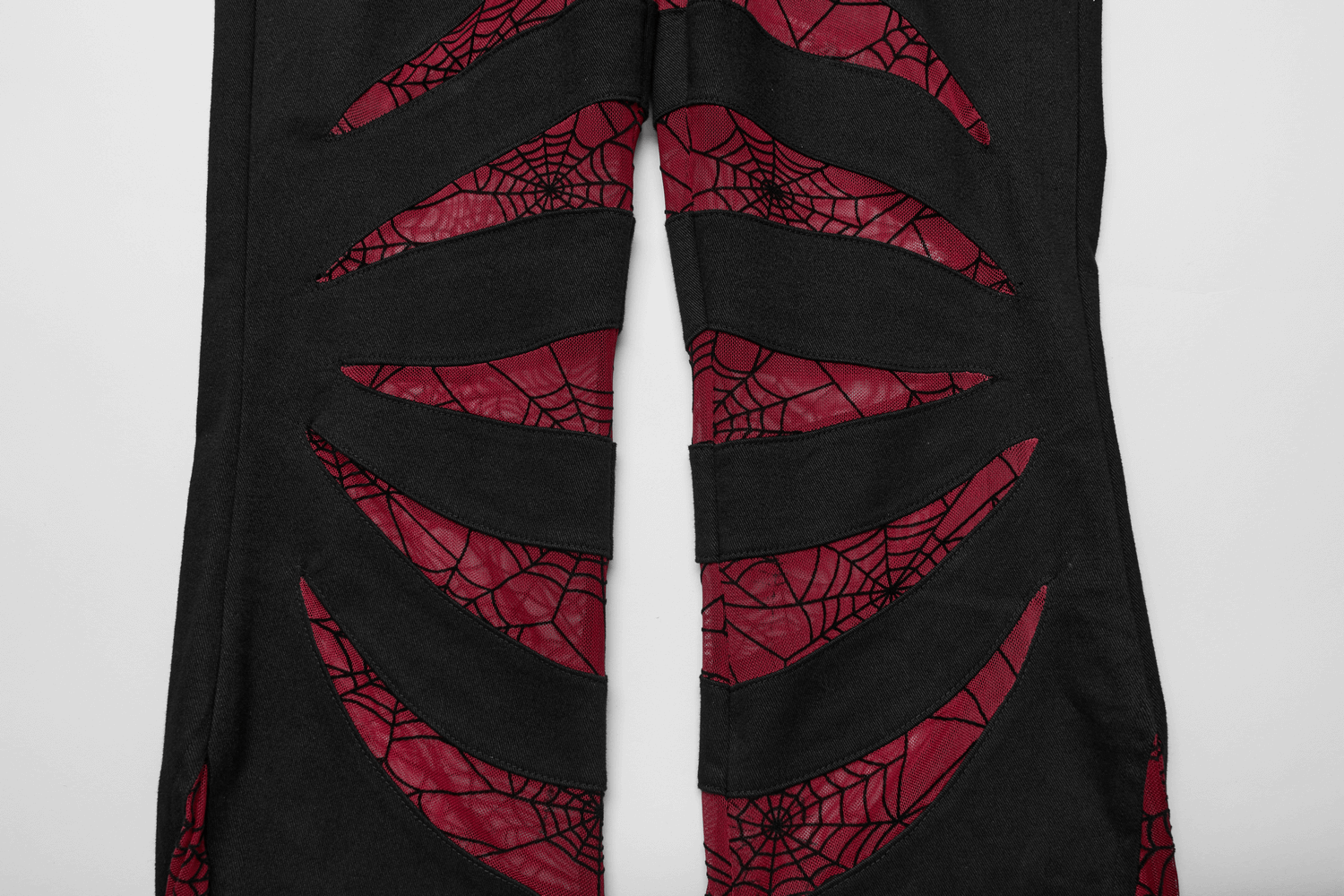 Goth-inspired black pants featuring red spiderweb mesh cutouts for a unique and edgy style.