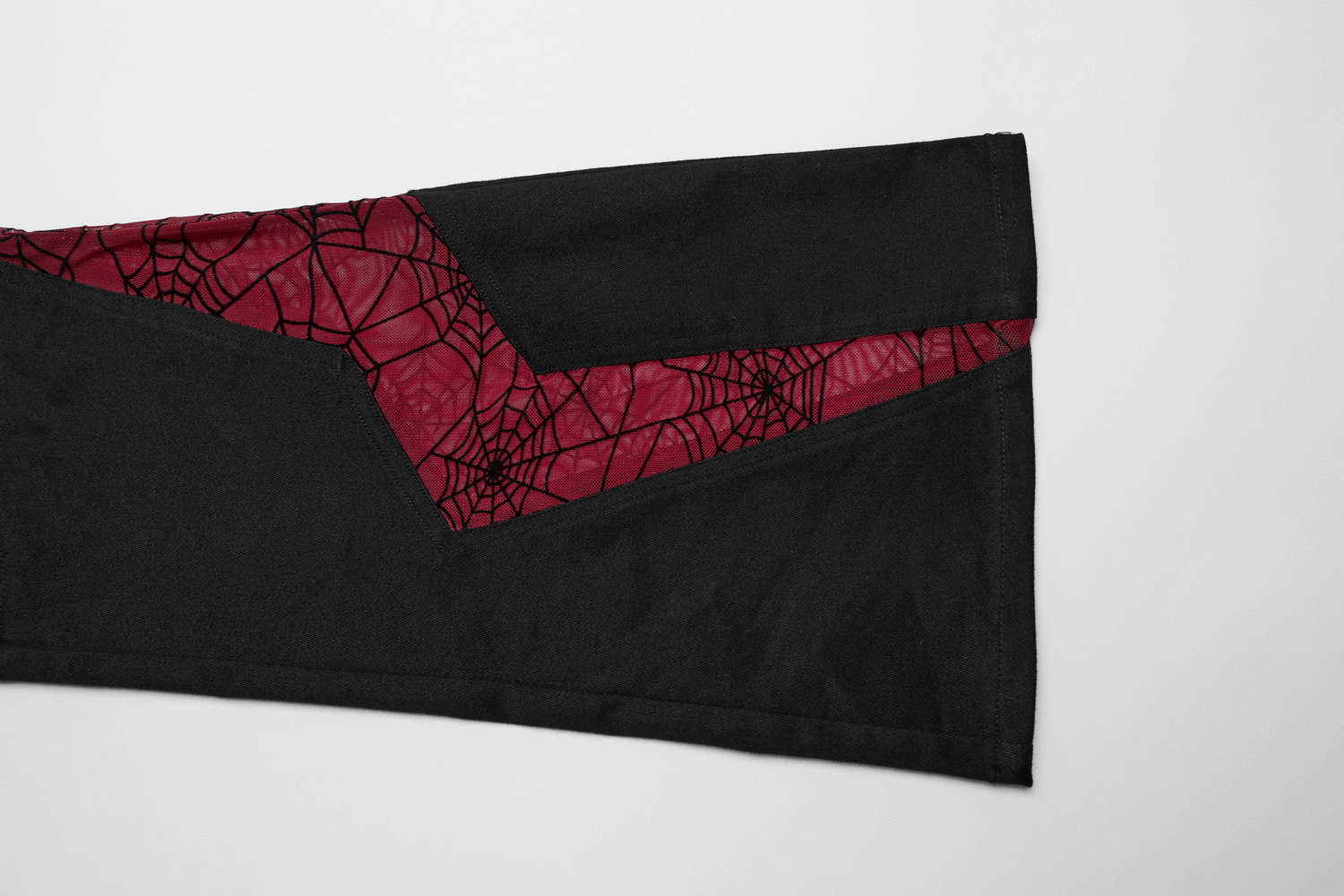 Close-up of black flared pants with red spiderweb mesh detailing.