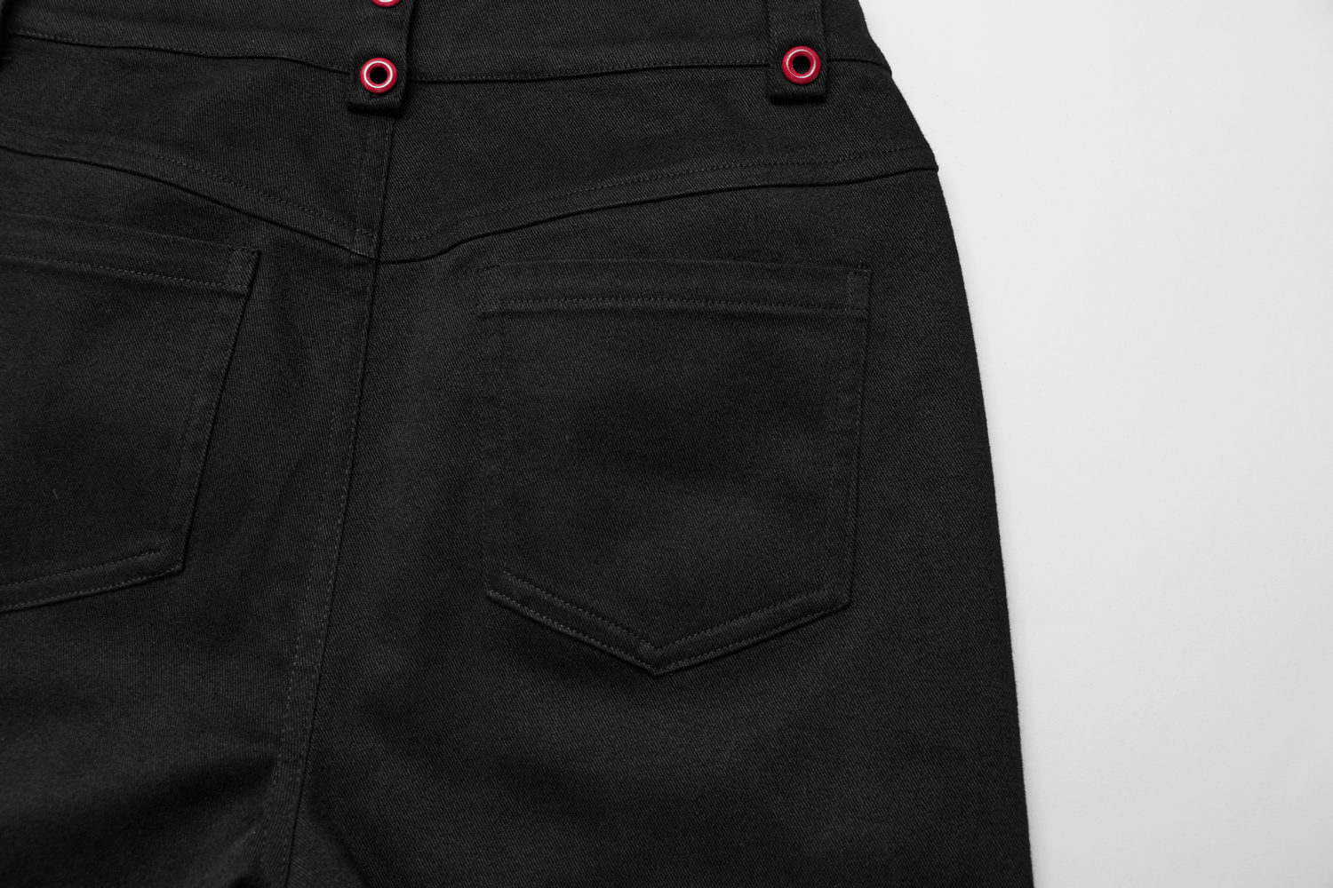 close-up of black gothic flared pants showcasing back pockets and red accent buttons for a stylish look