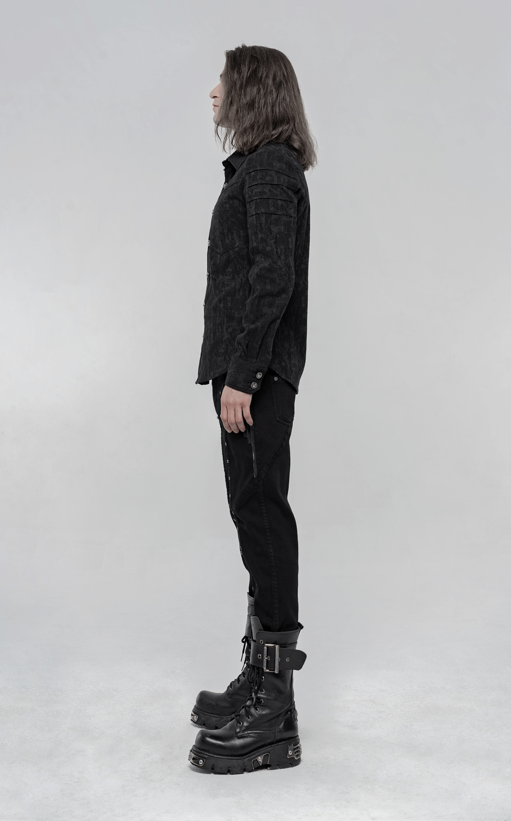 Side view of a man wearing a black stretch jacquard gothic shirt with unique button details and stylish punk boots.