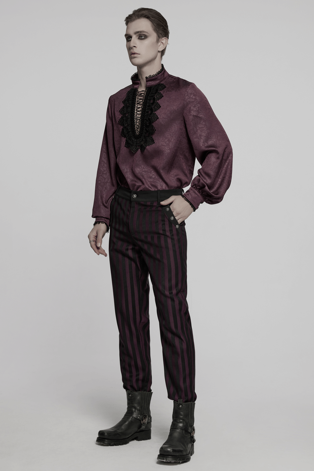 Fashion model showcasing striped black and burgundy slim gothic trousers paired with a stylish blouse and rugged boots.