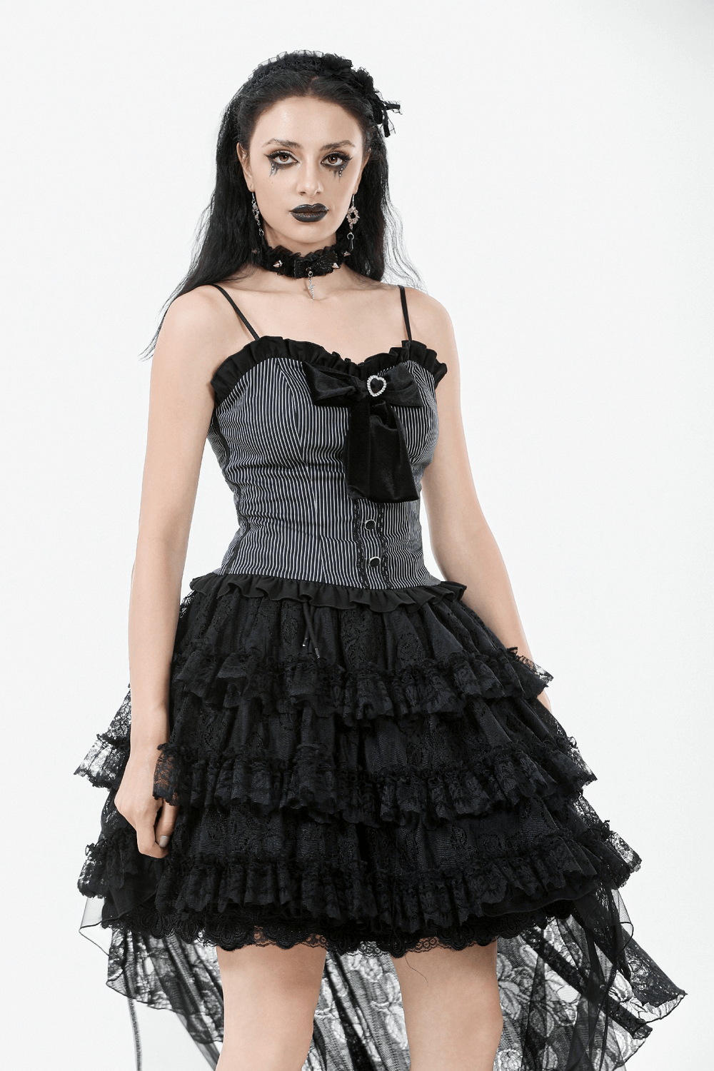 Gothic model wearing a black and white striped dress with ruffled lace skirt and heart bow detail.