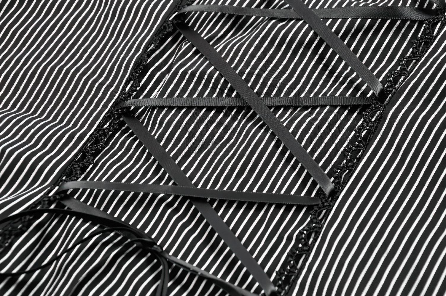 Close-up of lace-up back detailing on striped black and white top, showcasing stylish ribbon and lace accents.
