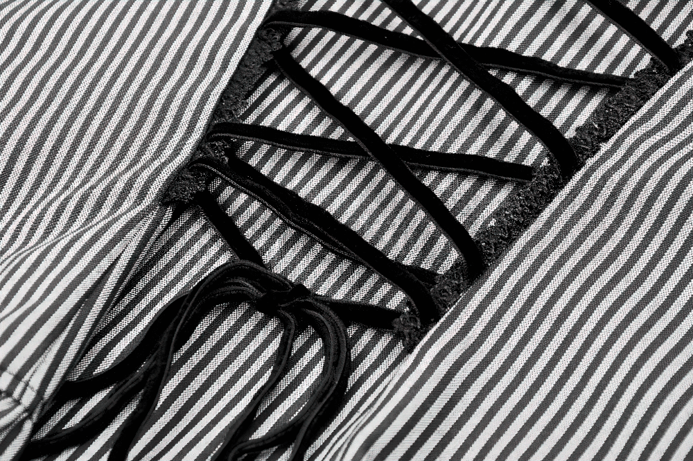 Close-up of gothic striped blouse showcasing lace-up back detail and ruffled edges.