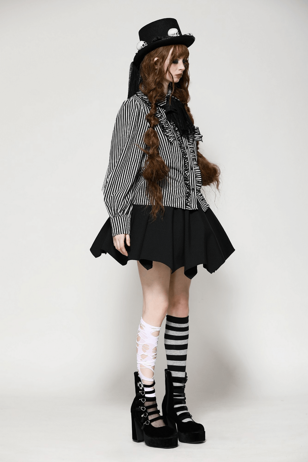 Striped Gothic blouse with lace details and skull charm, worn with a stylish black skirt and unique knee-high socks.