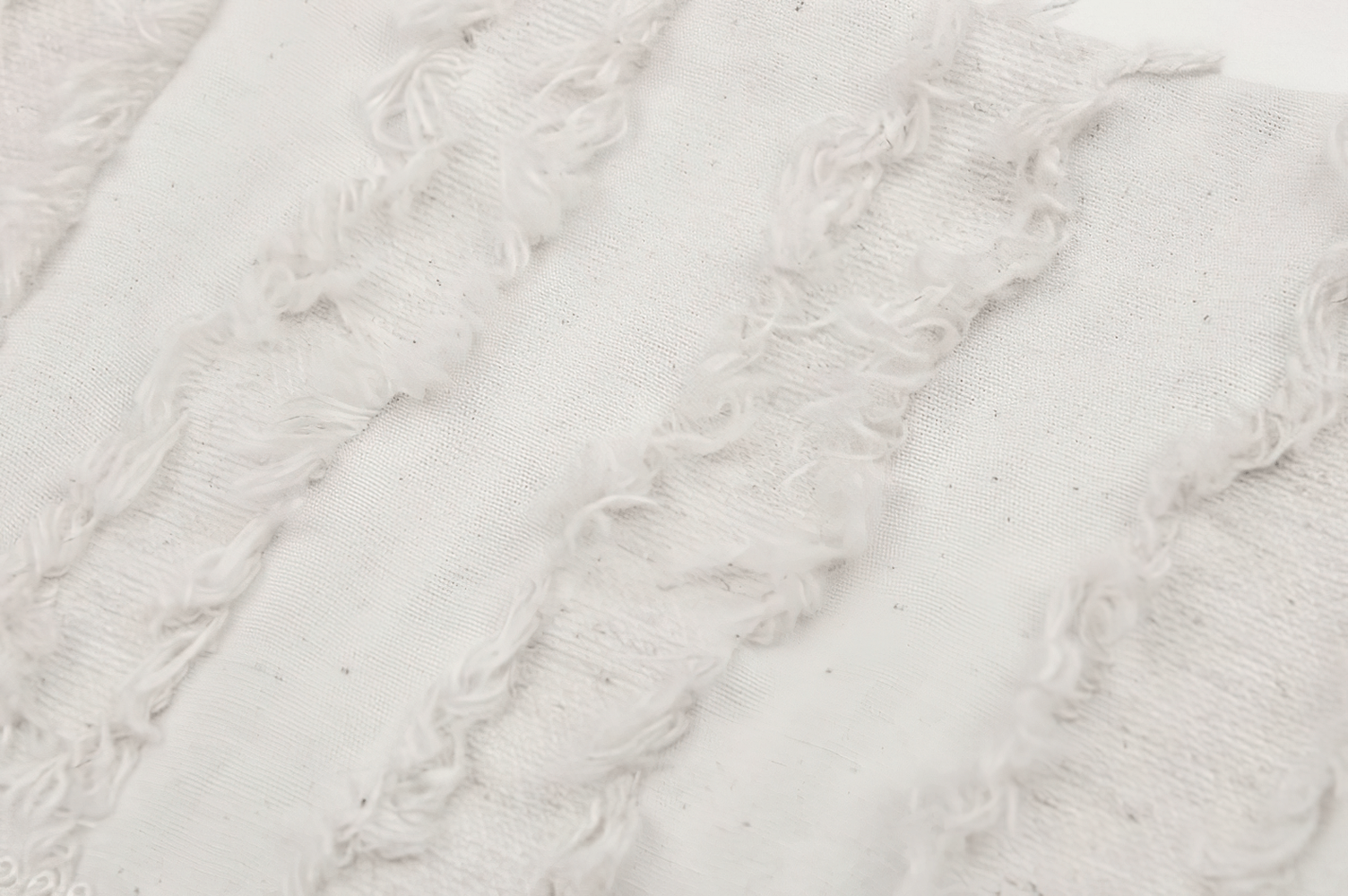 Close-up of soft white fabric with textured frayed stripes, ideal for stylish garment details.