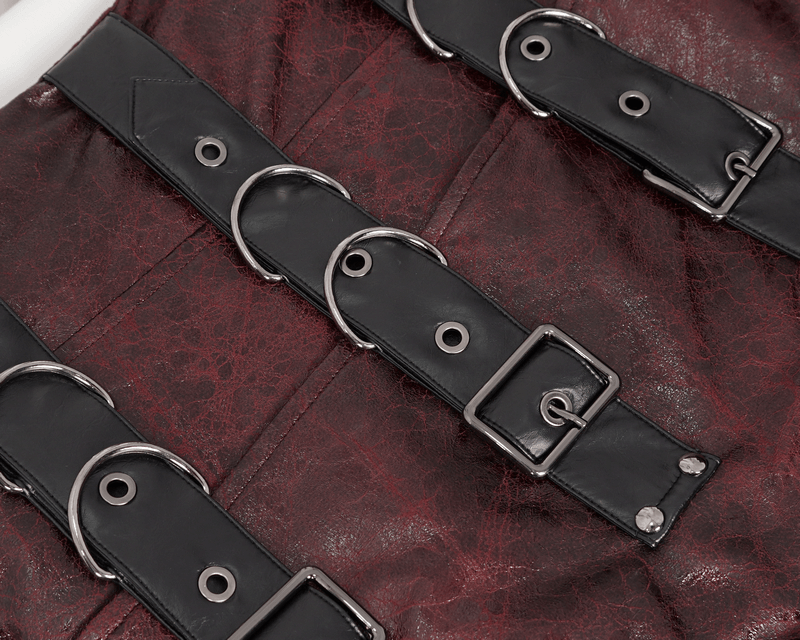 Close-up of studded black leather belts on a burgundy trench coat, showcasing edgy buckle details.