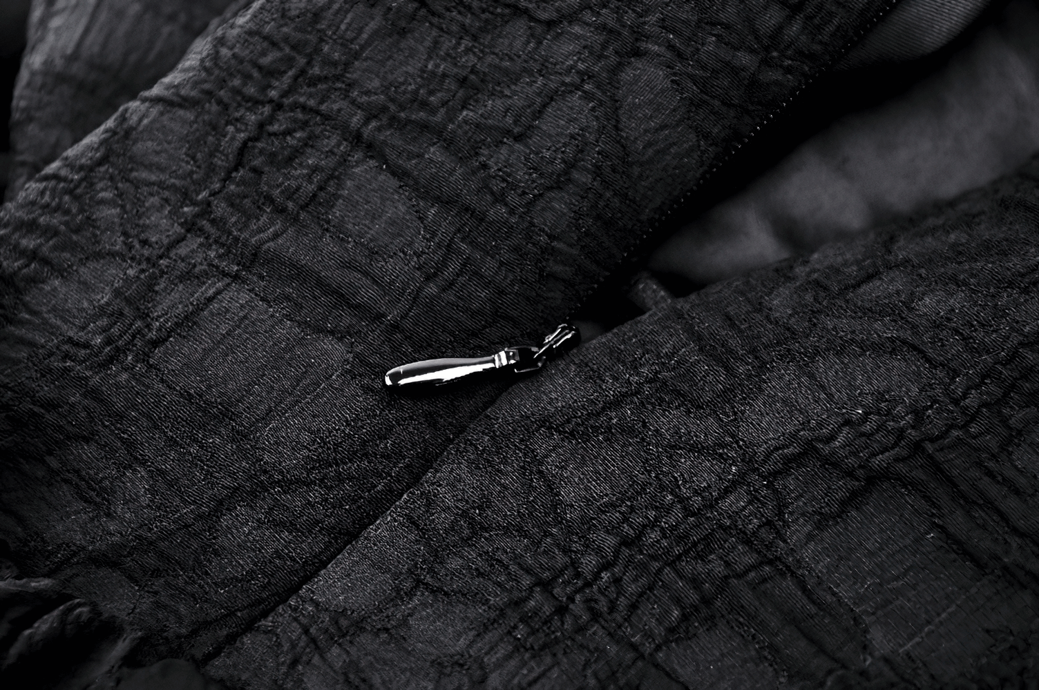 Close-up of a black lace fabric with a zipper detail, showcasing elegance for evening wear.