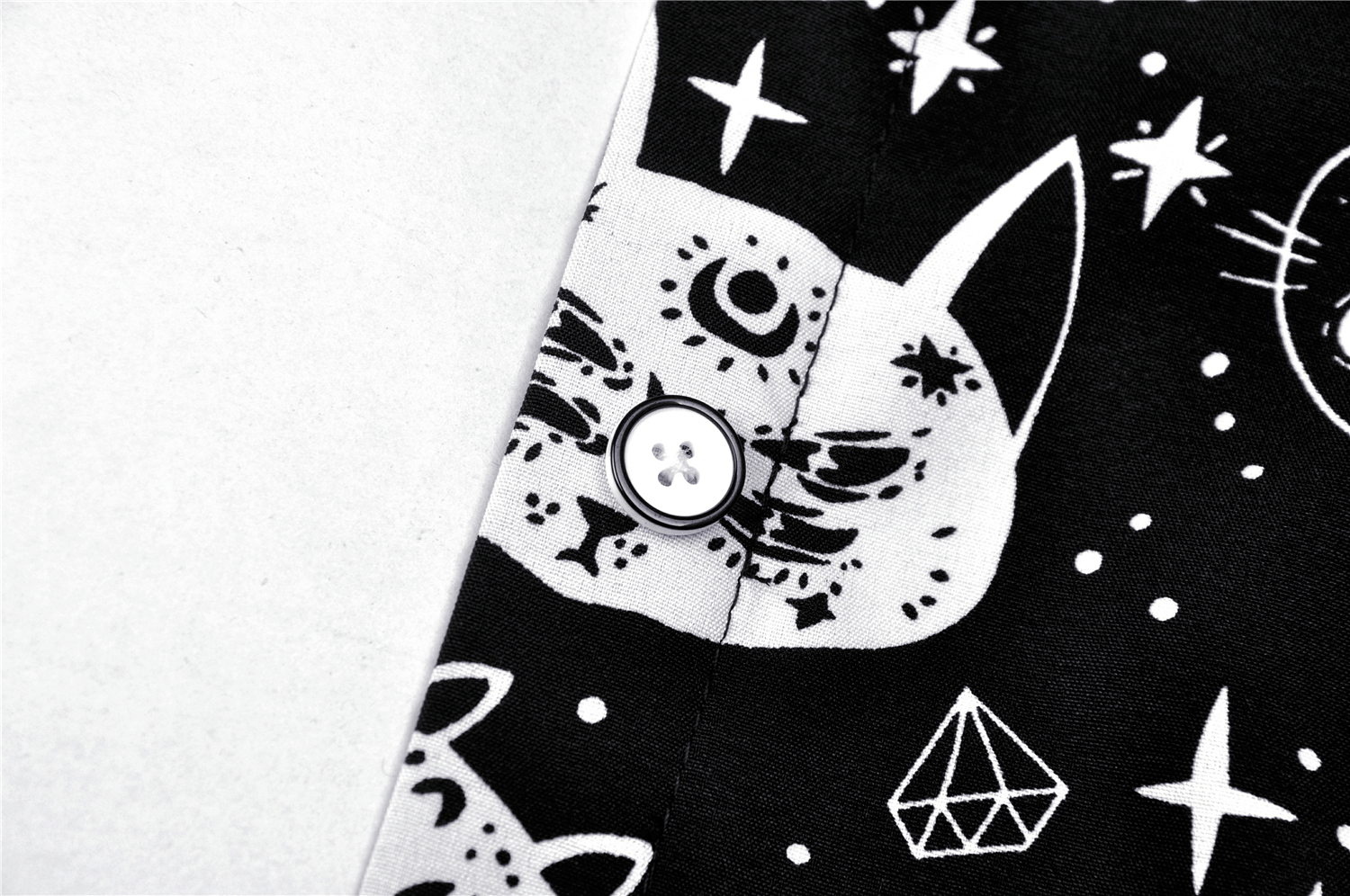 Close-up of stylish black and white cat print on gothic punk shirt with button detail.