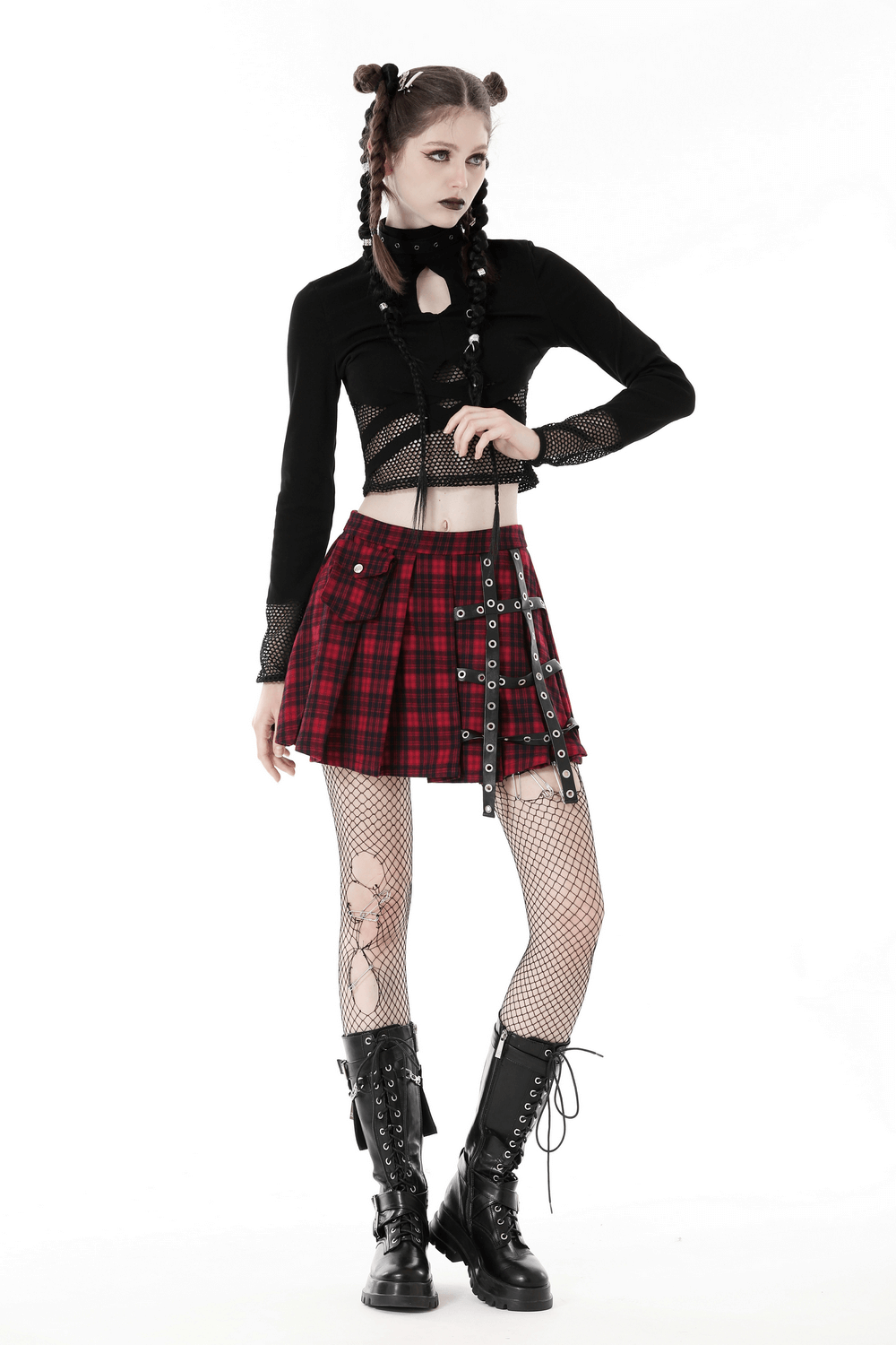 Punk-inspired model in black crop top with mesh sleeves, red plaid skirt, and black combat boots.
