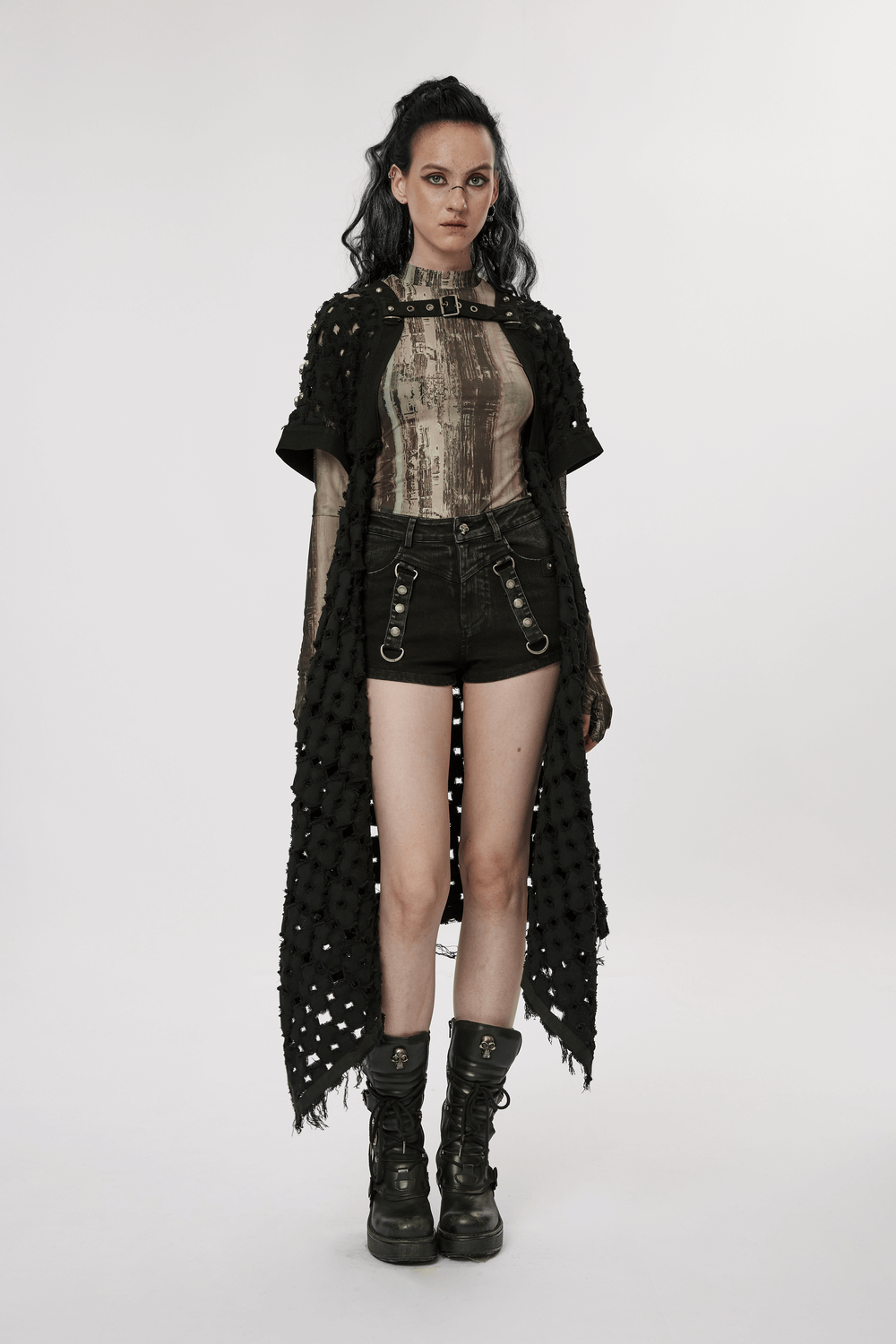 Edgy punk style model in black denim shorts-skirt with unique hollow-out design and layered outerwear.