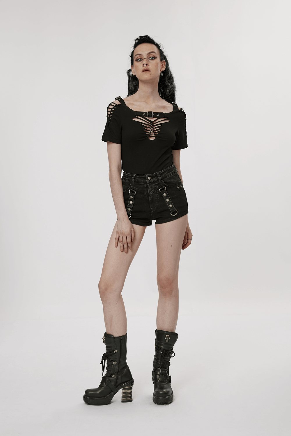 Model in edgy black denim shorts-skirt with unique cutouts and lace-up top, showcasing punk style fashion.