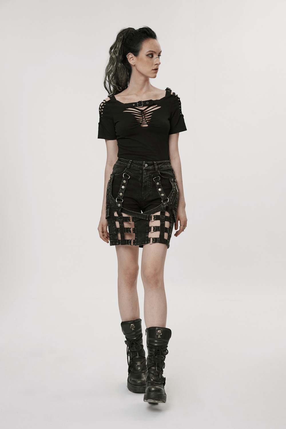 Edgy model in black denim shorts-skirt with unique cut-outs and stylish top, showcasing punk fashion vibes.