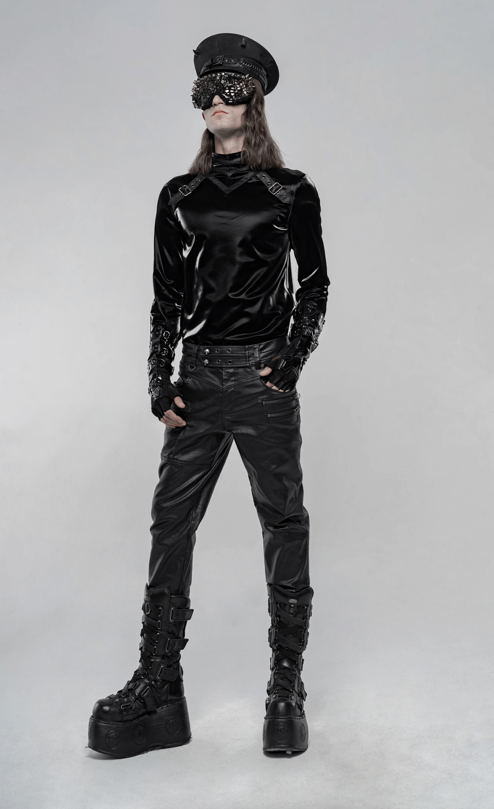 Edgy punk fashion model in stylish black faux leather pants with bold accessories and platform boots.
