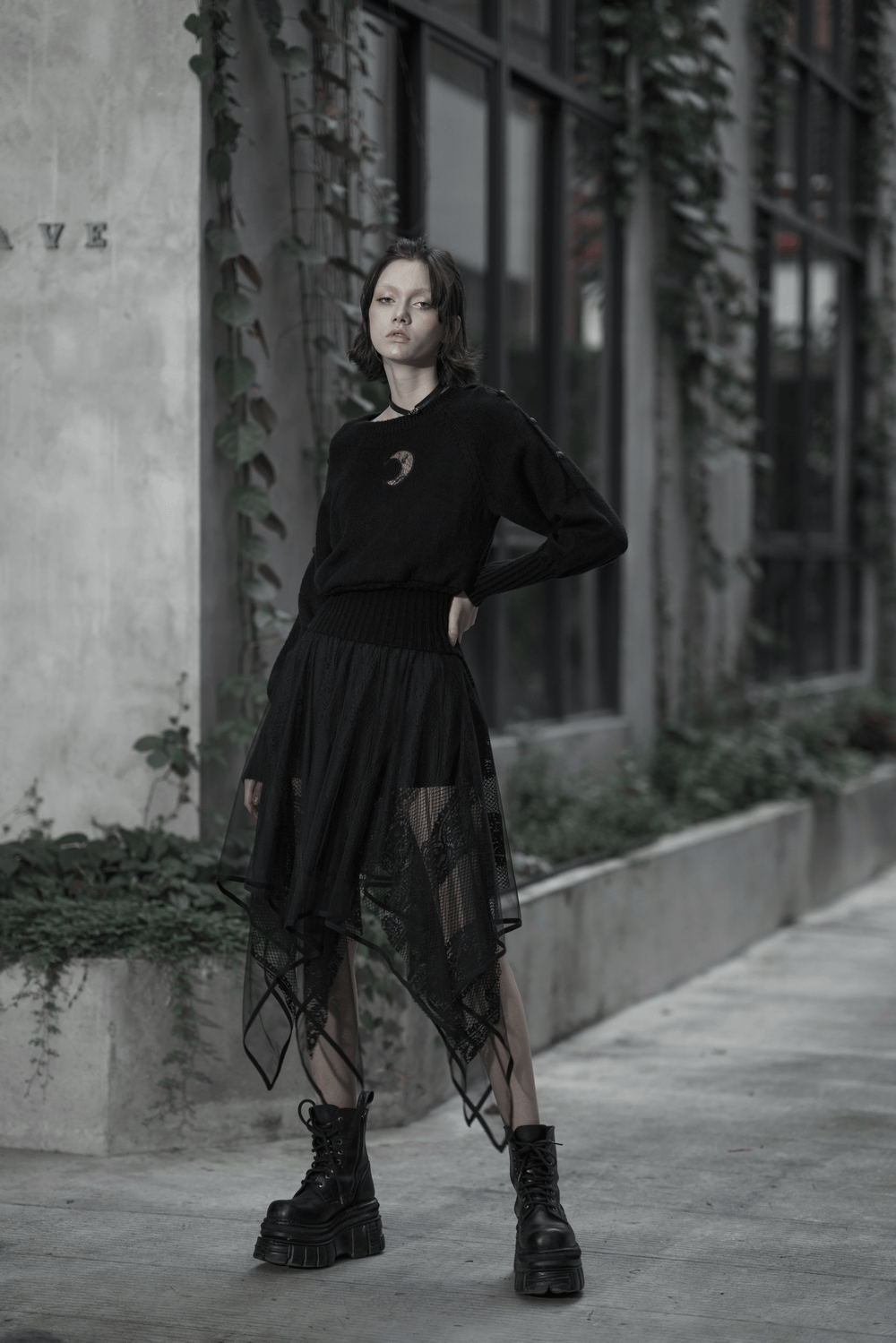 Model wearing a stylish black gothic layered mesh and lace skirt with a moon sweater and chunky boots.