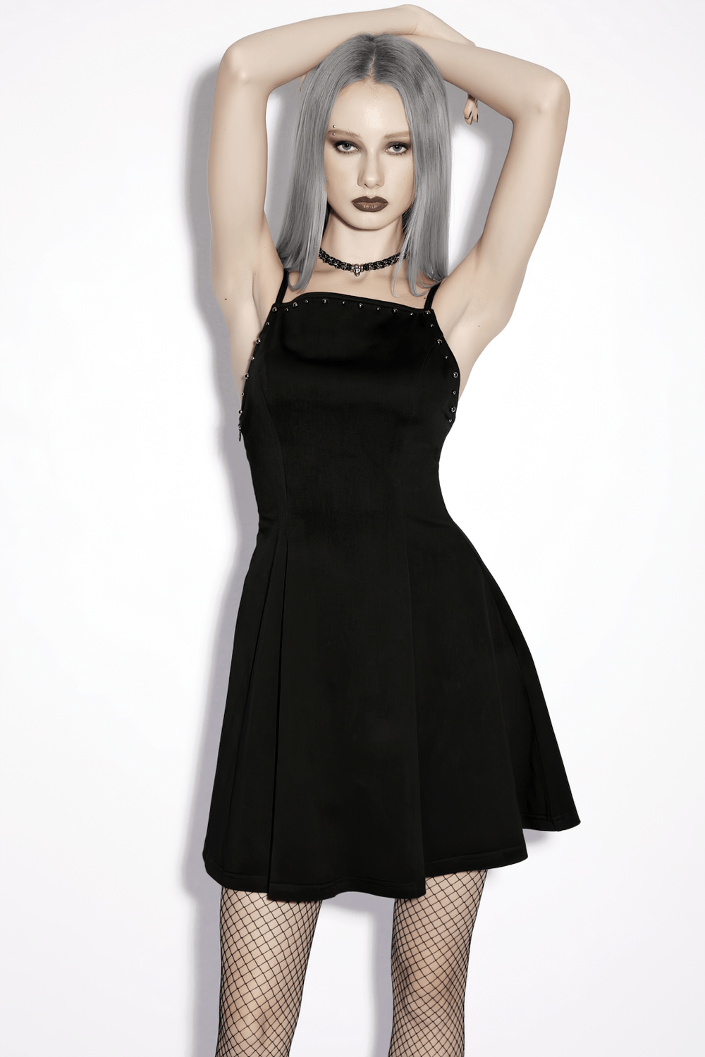 Alt Tag: Stylish Black Gothic Studded Strappy A-Line Mini Dress on model, square neck slip dress with metal studs, fishnet tights, edgy gothic look
