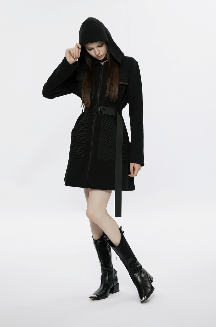Model showcasing a stylish black hooded zip-front tactical dress with pockets and adjustable buckle belt.