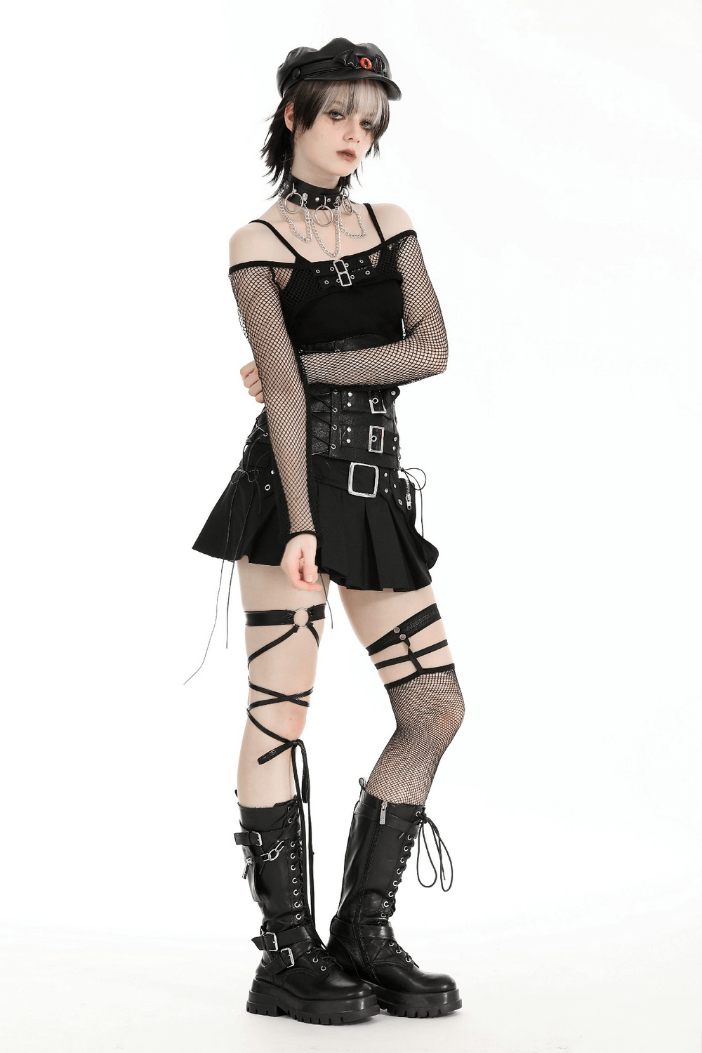 Trendy black long sleeved fishnet top with buckles, paired with a stylish skirt and edgy accessories.