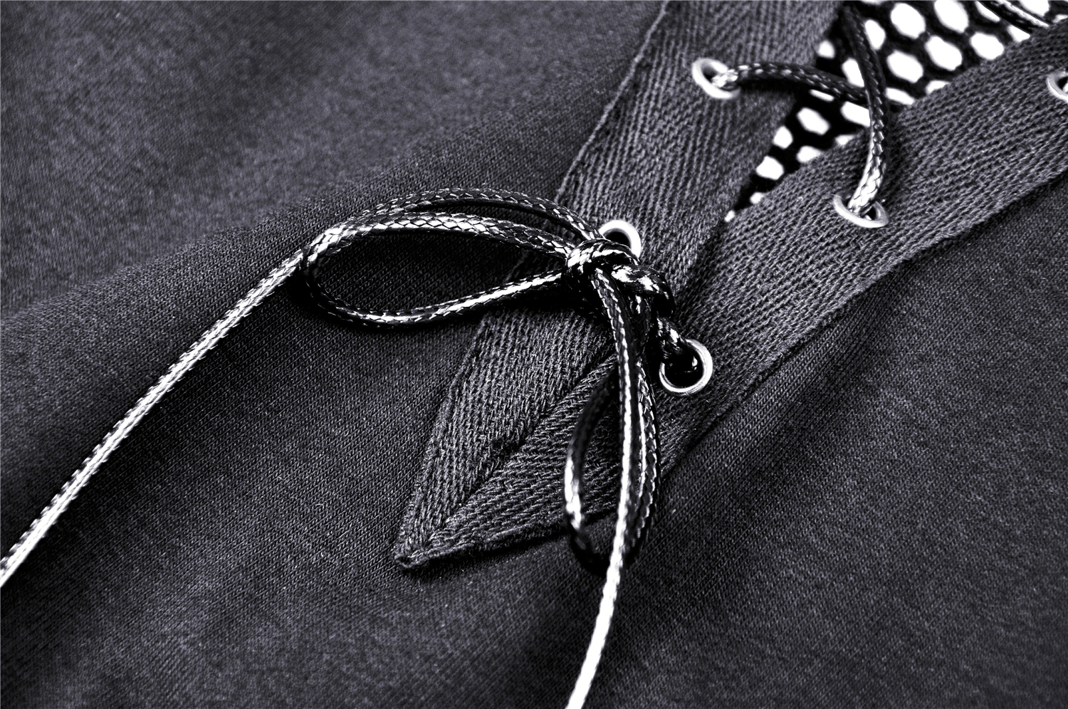 Close-up of black mesh crop top featuring lace-up detailing and fishnet sleeves for a punk style look.