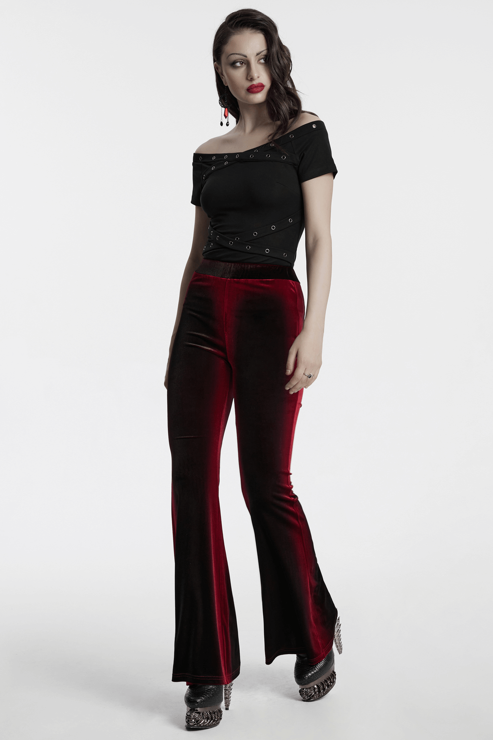 Stylish black off-shoulder T-shirt with eyelet details paired with red velvet flares for a bold look.