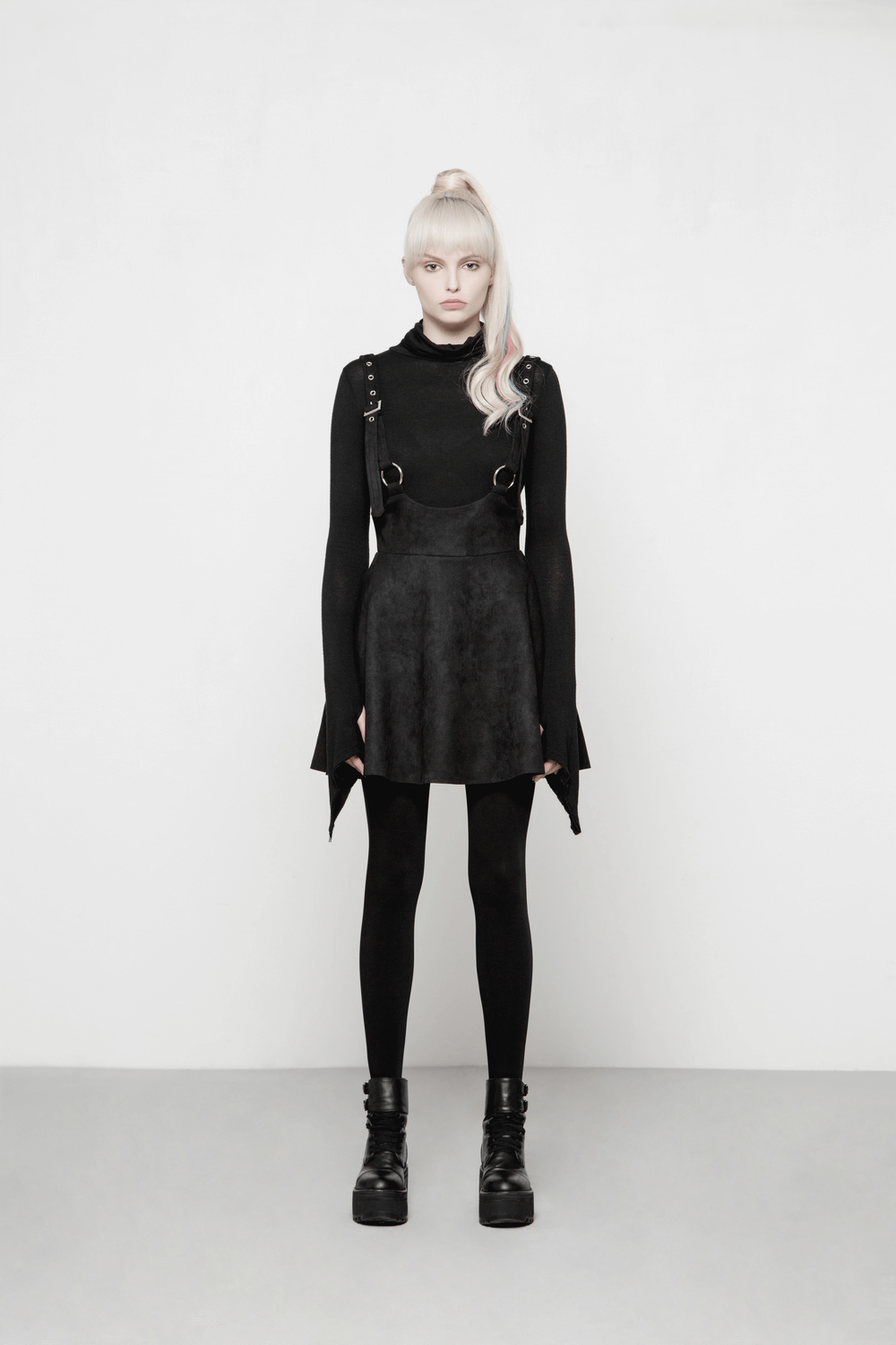 Model wearing a stylish black suspender mini skirt with metal rings and a fitted top, embodying punk rock fashion.