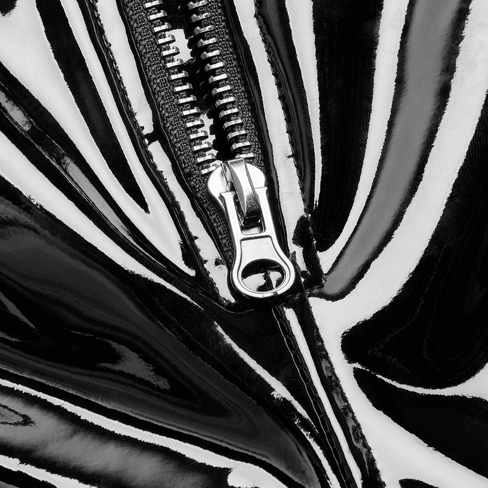 Close-up of high-shine black vinyl leggings featuring a sleek side zipper for a stylish edge.