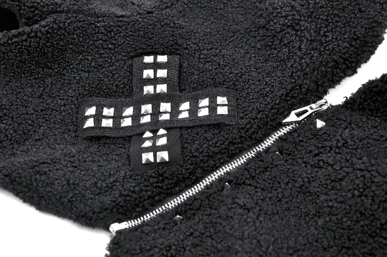 Close-up of black fleece hoodie featuring silver spikes and decorative cross design, showcasing edgy style.
