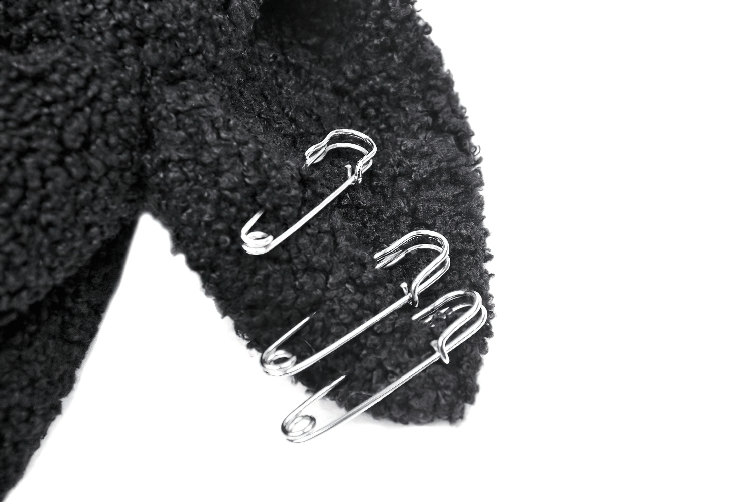Close-up of a black plush hoodie sleeve with silver safety pins for an edgy touch.