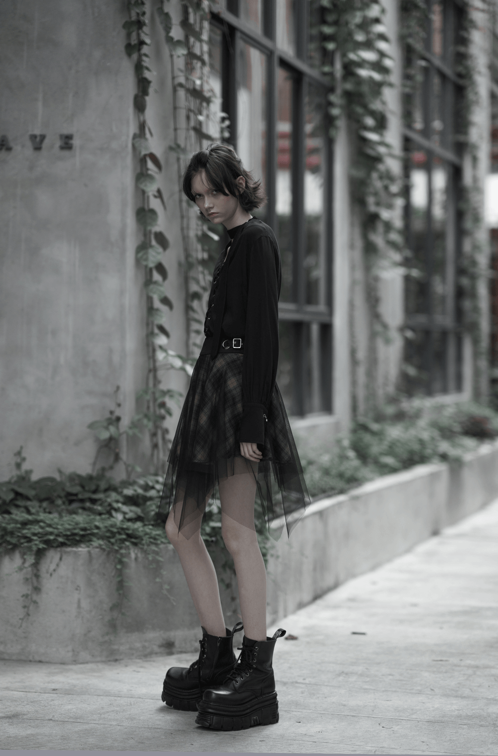 Edgy dark punk grunge plaid mesh asymmetric skirt styled with a chic top and chunky boots in a urban setting.