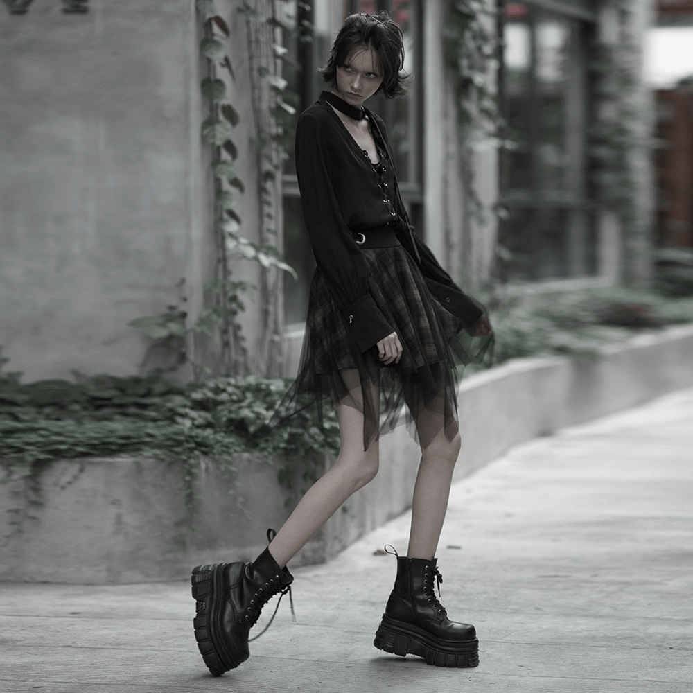 Model wearing a stylish dark punk grunge plaid mesh asymmetric skirt with chunky combat boots.