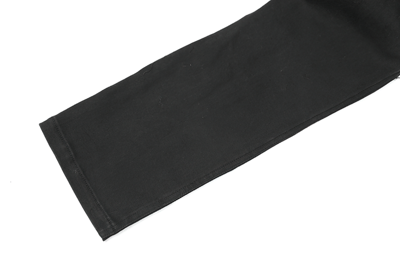 Close-up of the leg of stylish distressed knee-patch punk men's trousers in black denim.