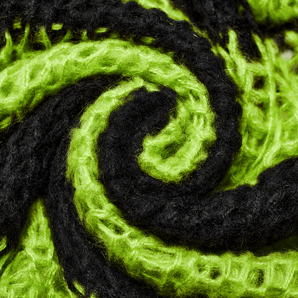 Close-up of twisted black and green mohair yarn showcasing a stylish distressed texture.