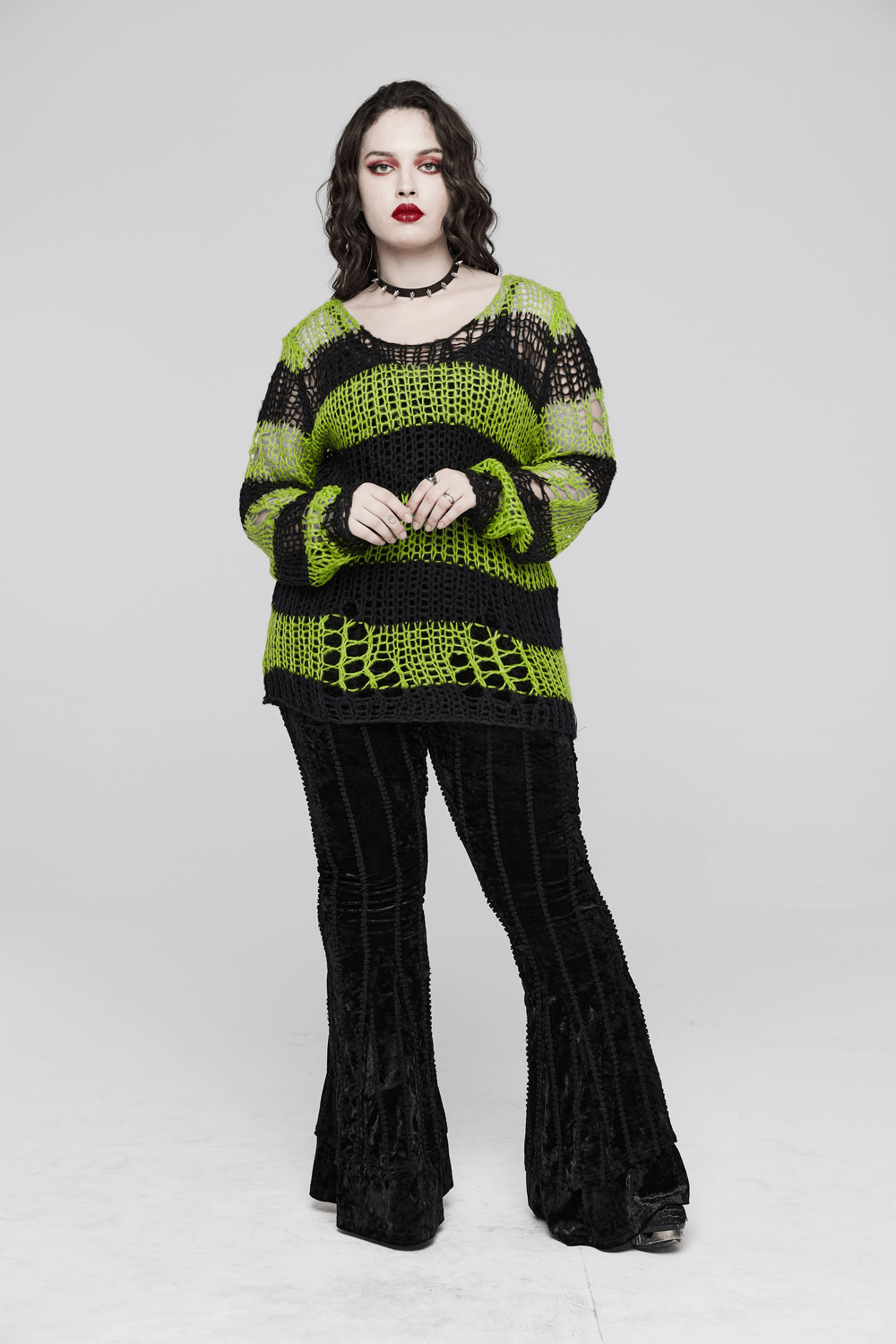 Model wearing a stylish distressed striped mohair pullover sweater with edgy holes, paired with black flared pants.