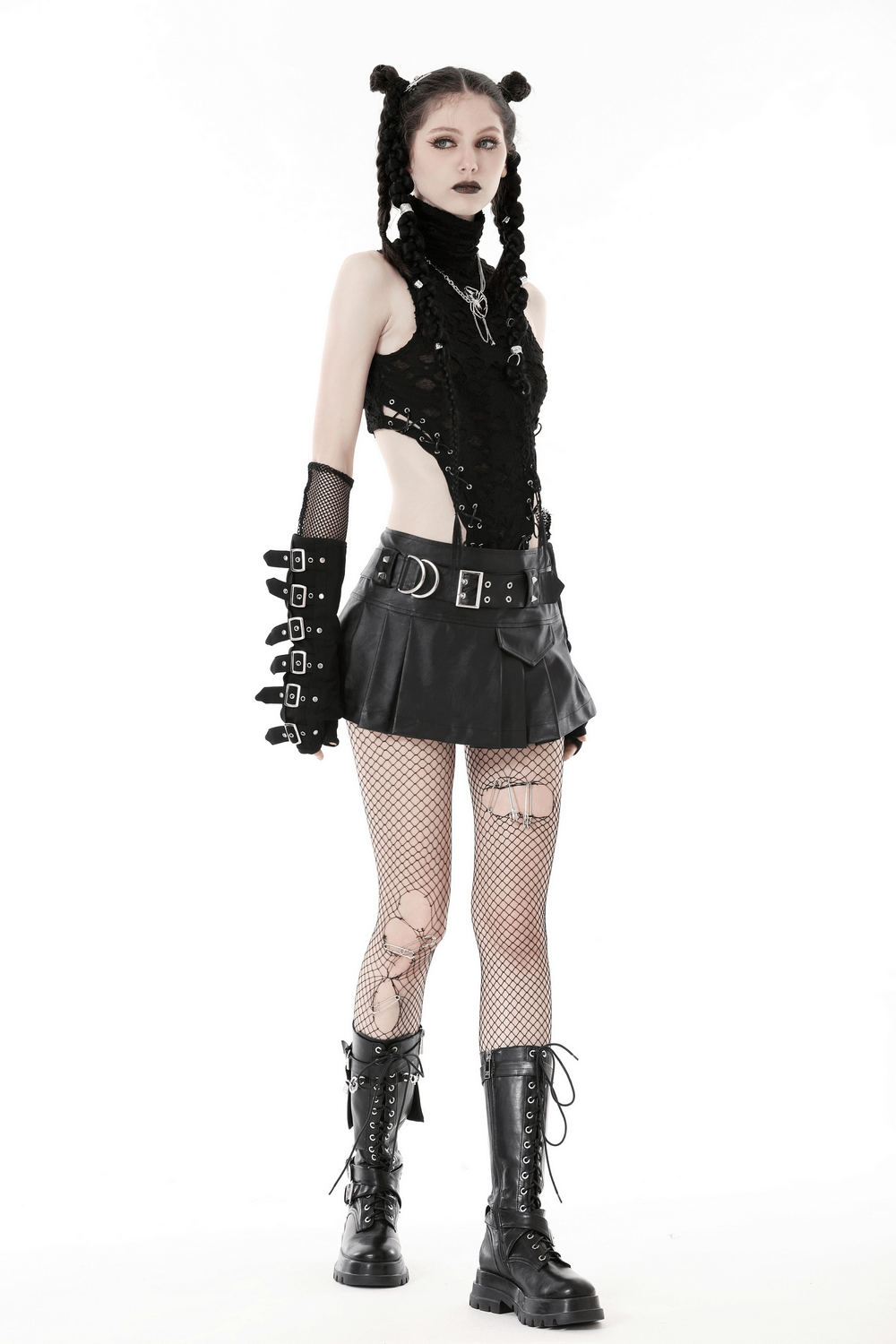 Edgy model in black faux leather pleated mini skirt, fishnet tights, and combat boots showcasing gothic punk style.