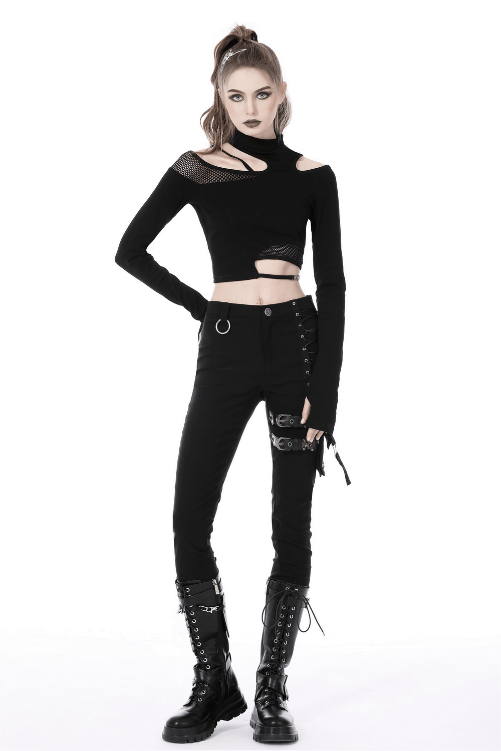 Gothic female model in black asymmetrical off-the-shoulder punk top and stylish pants, showcasing dark aesthetic fashion.