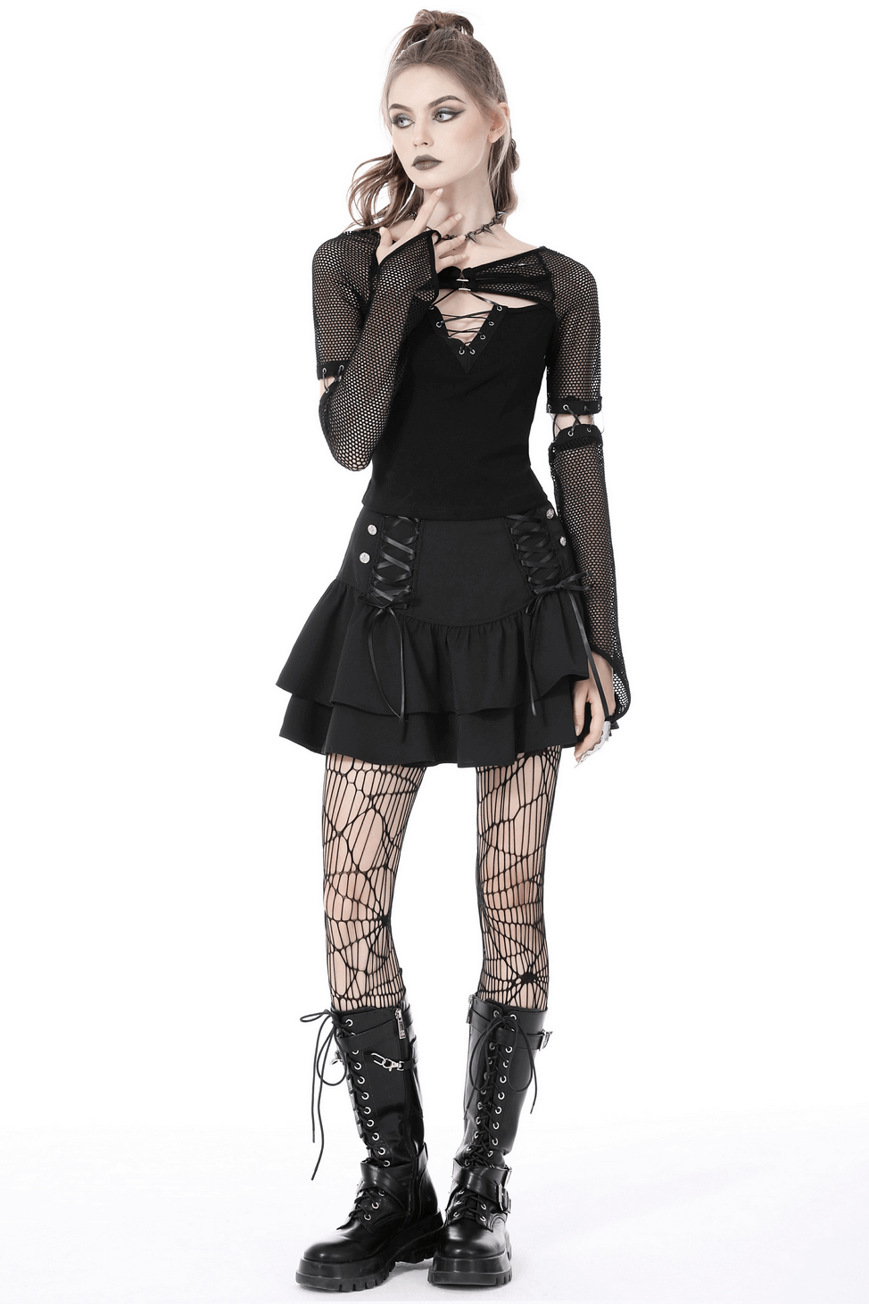 Stylish female in a black mesh goth top with lace-up sleeves and skirt, paired with fishnet tights and combat boots.
