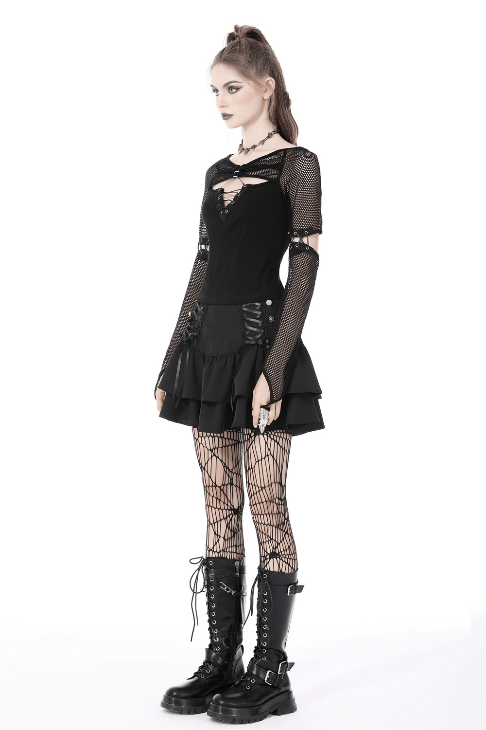 Stylish female in a black mesh goth top with lace-up sleeves, layered skirt, and combat boots, showcasing a bold goth aesthetic.