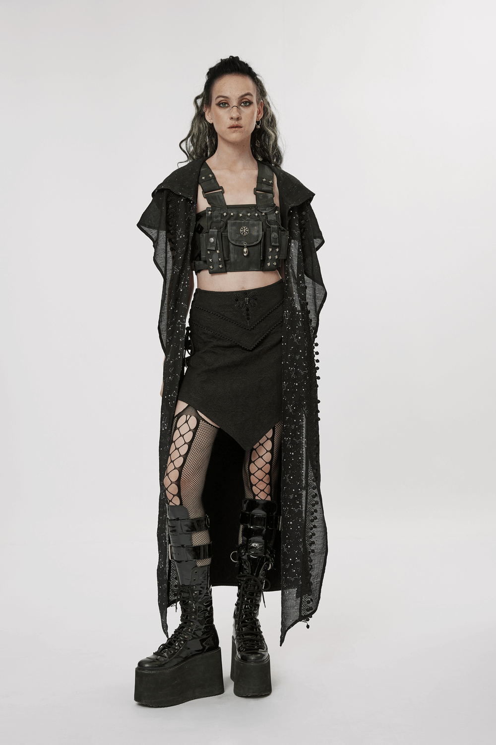 Stylish model in black punk outfit with corset, long coat, and platform boots, showcasing edgy fashion.