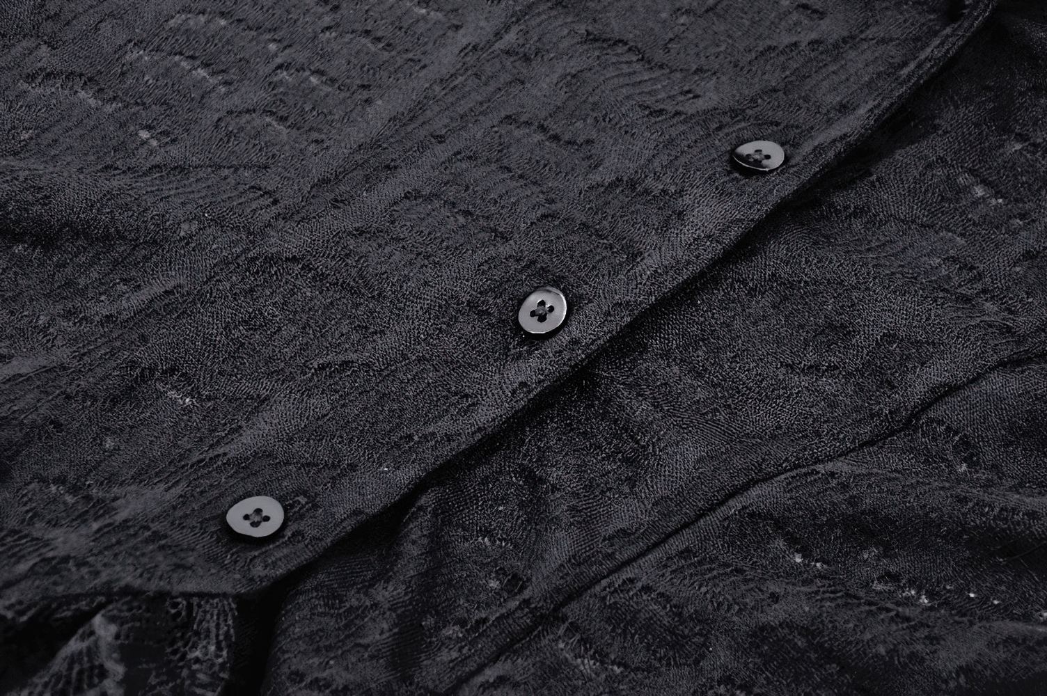 Close-up of stylish black gothic blouse showcasing intricate lace texture and elegant button details.