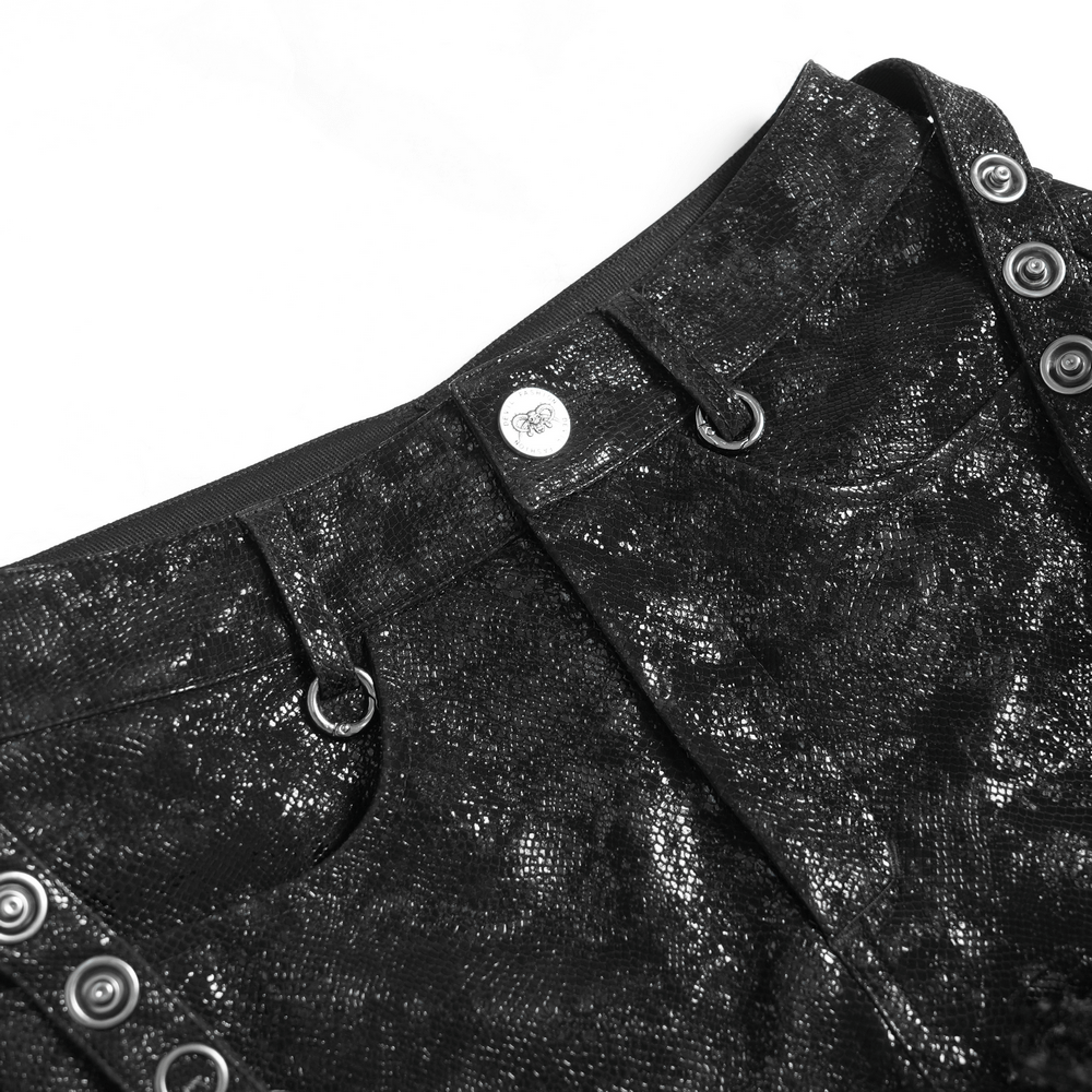 Close-up of stylish gothic black faux leather shorts featuring metal buttons and rings, perfect for edgy fashion.