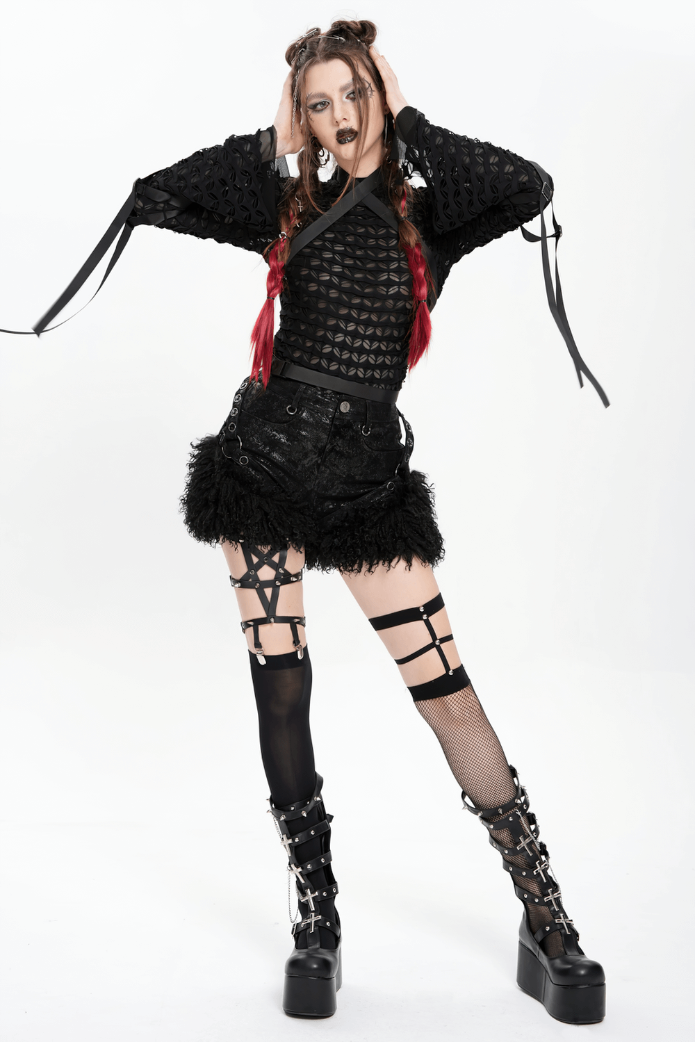 Stylish Gothic model in black faux leather shorts with fur trim, strappy stockings, and edgy platform boots.