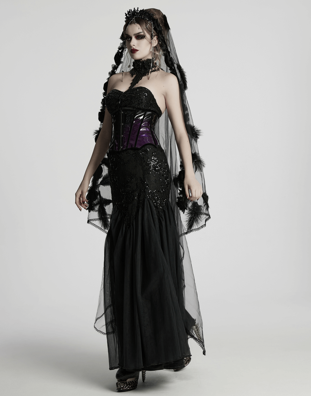 Gothic model in elegant black dress and glossy gradient underbust corset, showcasing bold punk style.